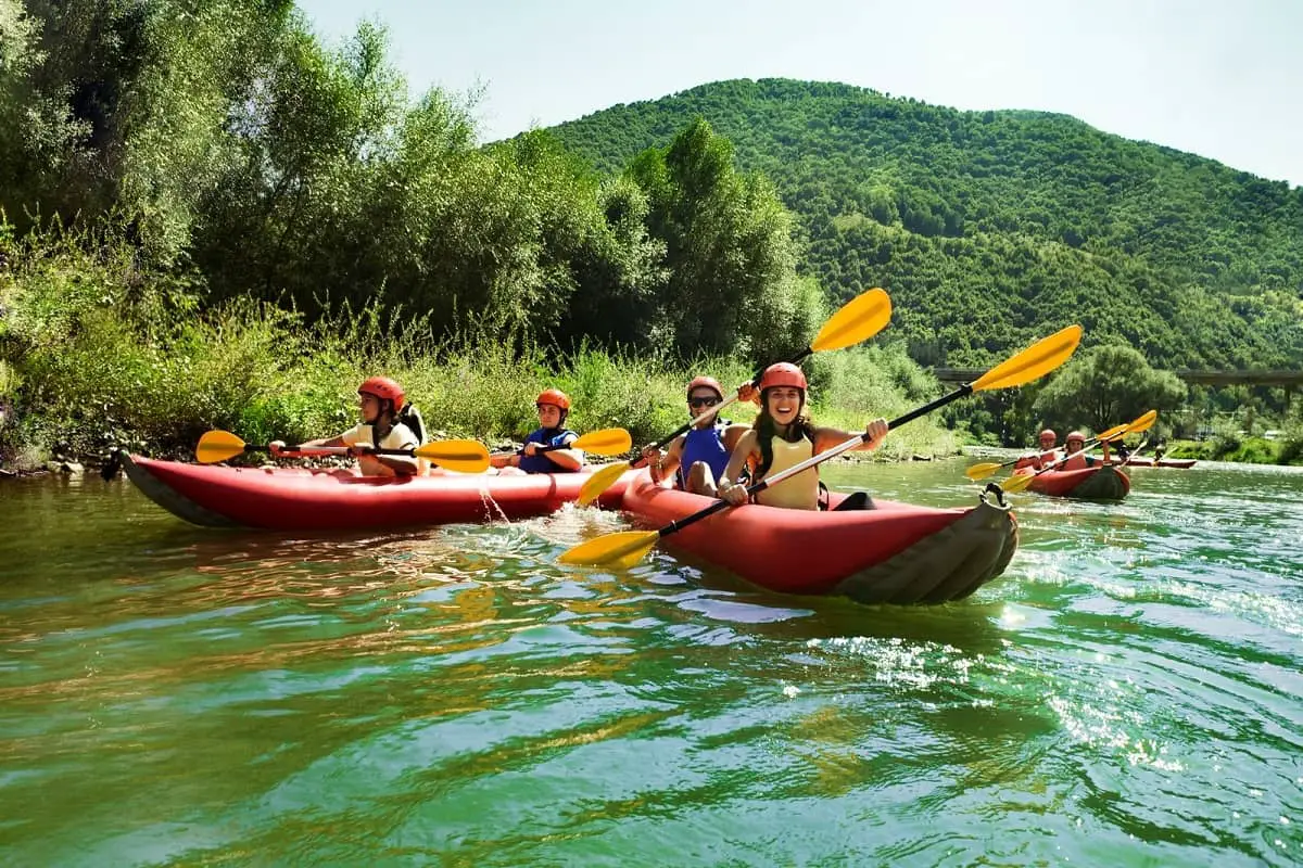 Group of people canoeing wearing water sports helmets