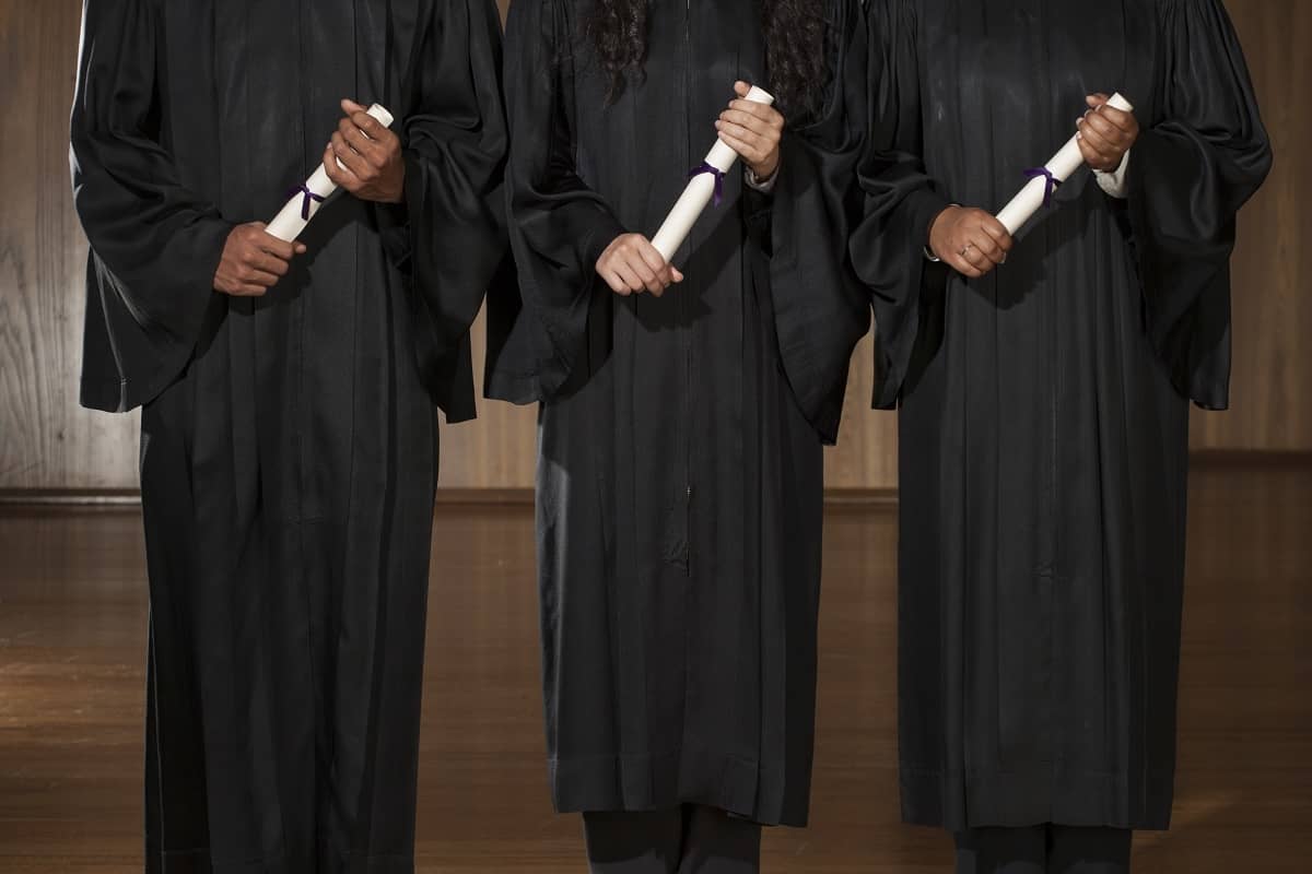 Three college graduates holding certificates