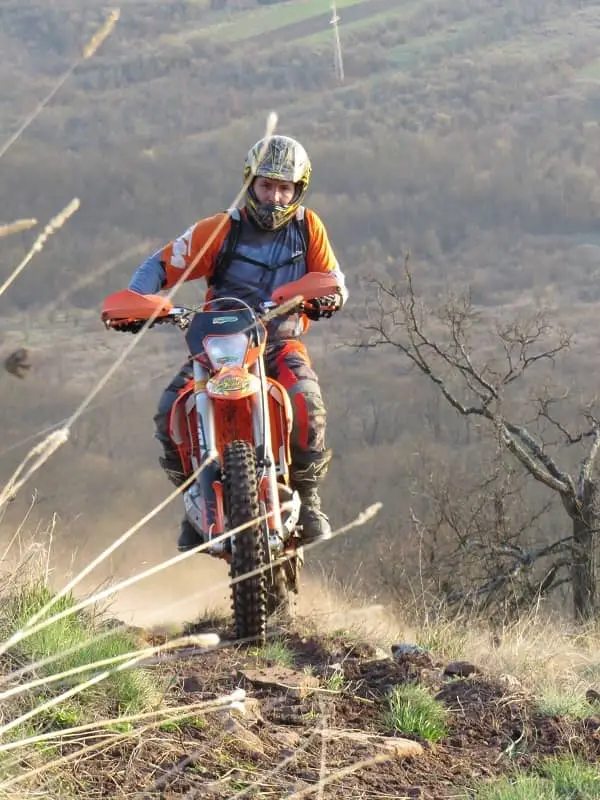 Man riding red dirt bike on country trail