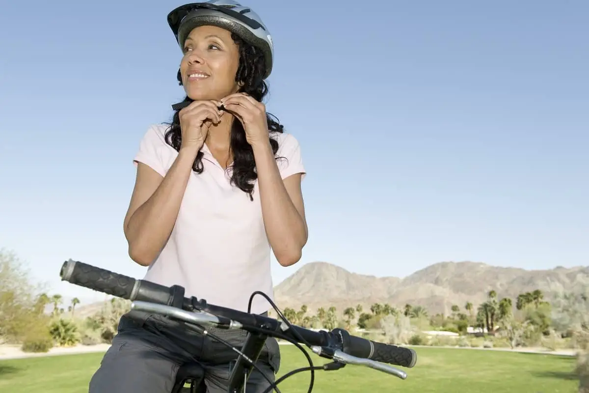 Woman cyclist tightening chin strap on helmet