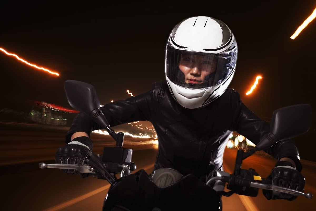 Woman riding motorcycle at night in city