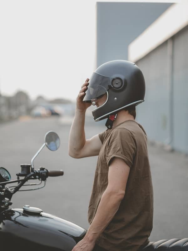 Man on motorbike adjusting helmet visor