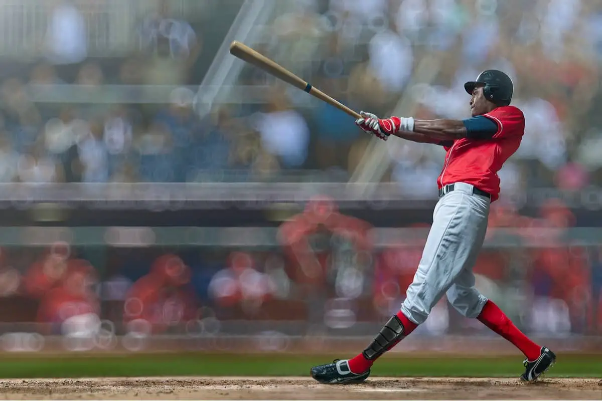 When did baseball players start wearing helmets? This baseball batter wearing a red shirt hits the ball while wearing his helmet.