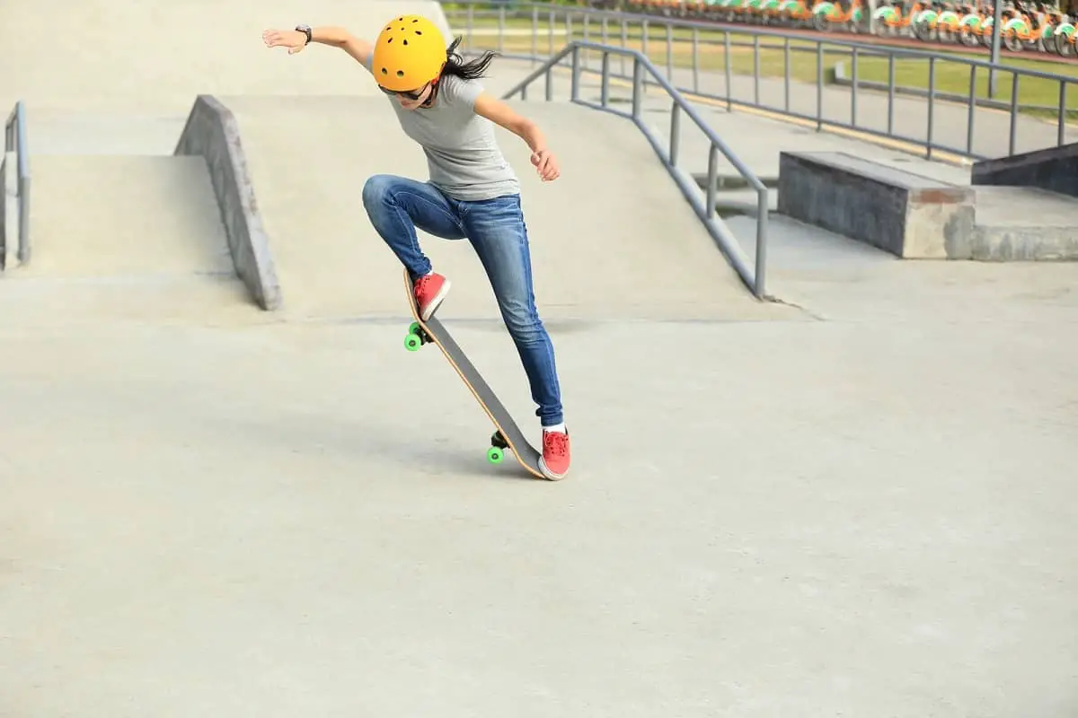 Teenage girl doing tricks on skateboard