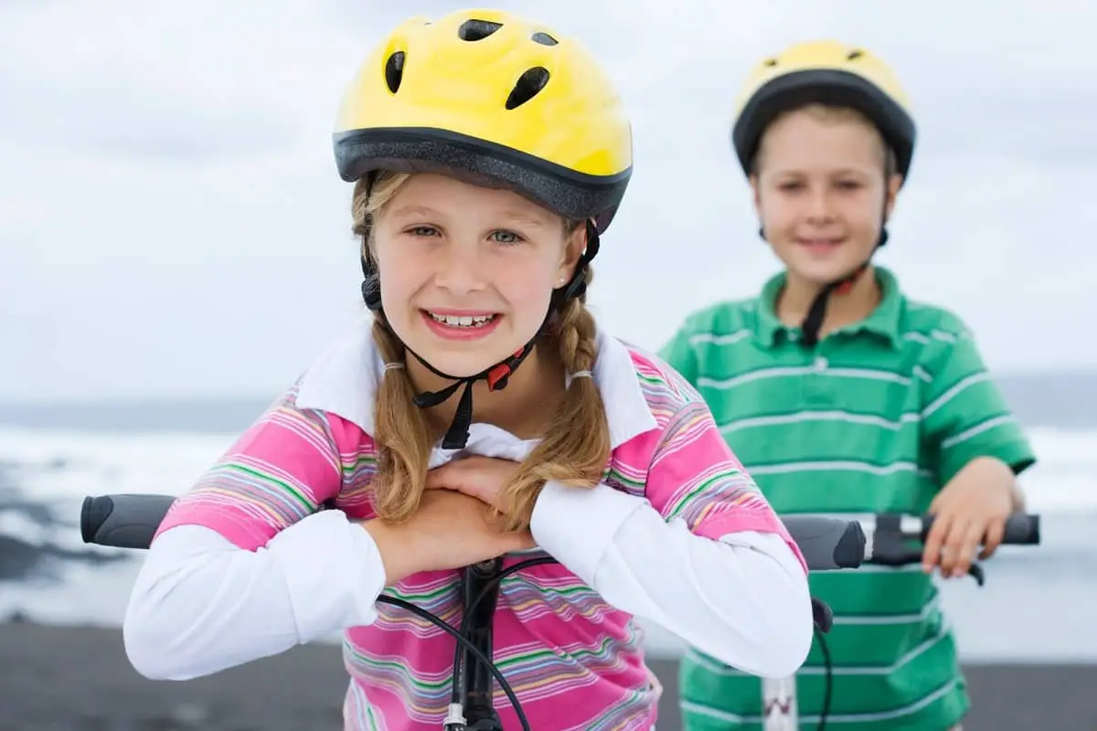2 young kids wearing yellow bike helmets