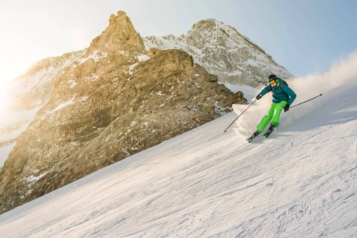 Snow skier skiing down steep slope