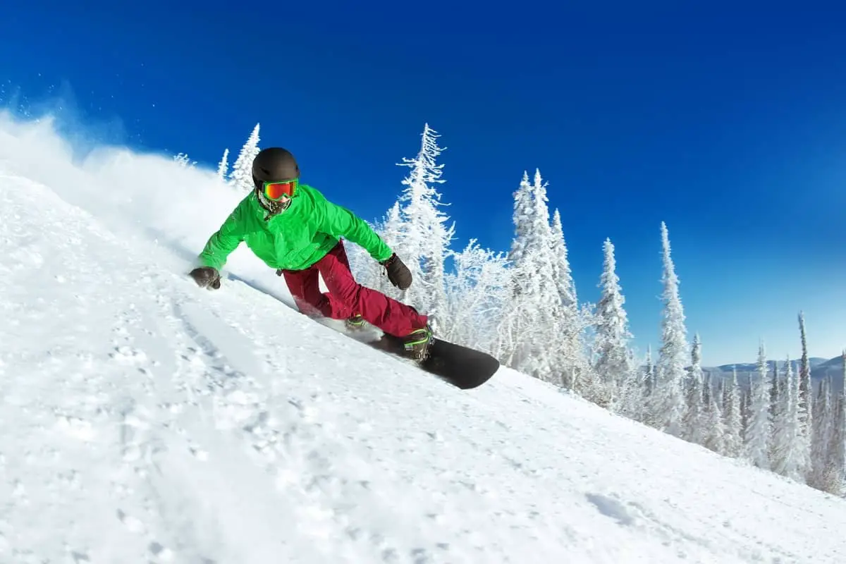 Snowboarder on steep slope wearing bright green jacket and black helmet