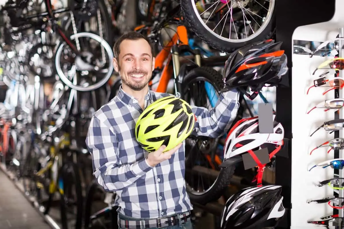 A salesman in a shop showing the different types of bike helmets.