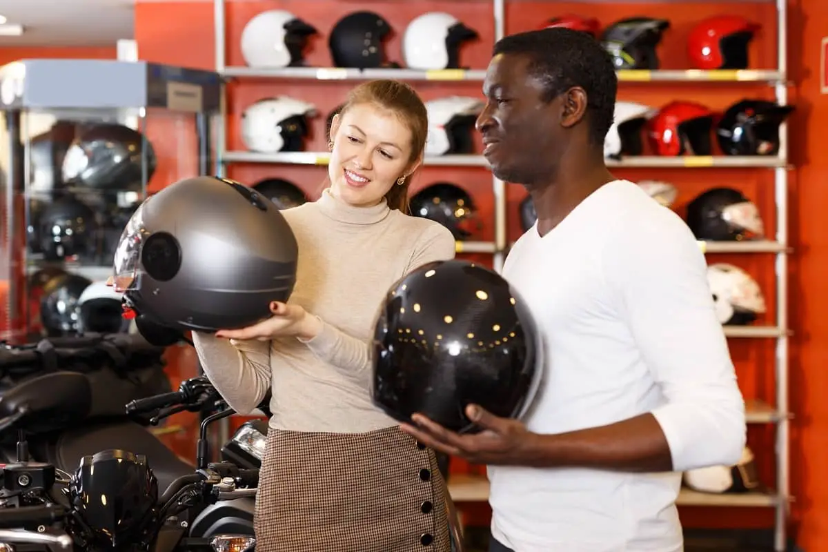 Sales woman showing silver motorcycle helmet to customer