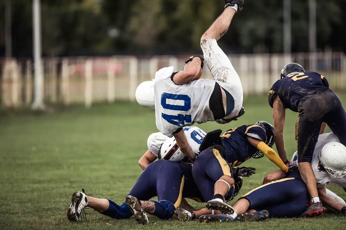 footballer in white uniform in the air above players in blue uniforms