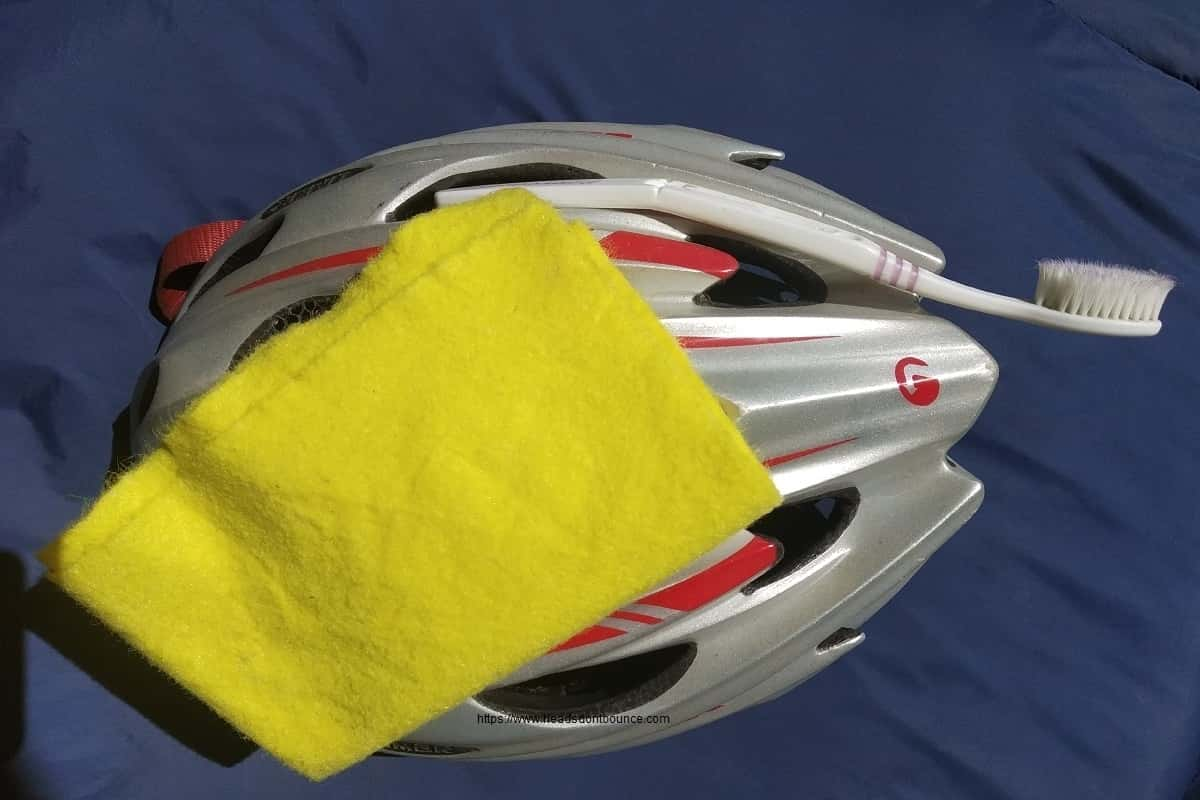 Grey and red helmet with yellow wash cloth and toothbrush on blue background