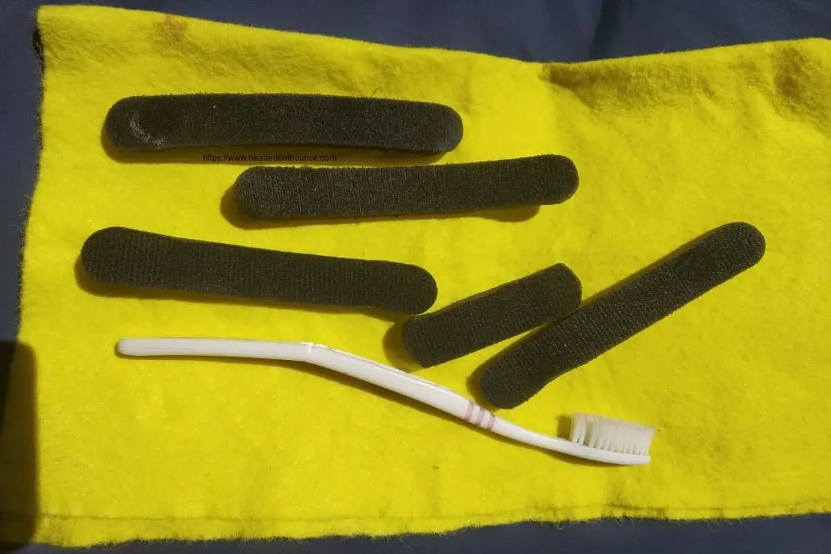 Bicycle helmet pads on yellow cloth with toothbrush ready for cleaning
