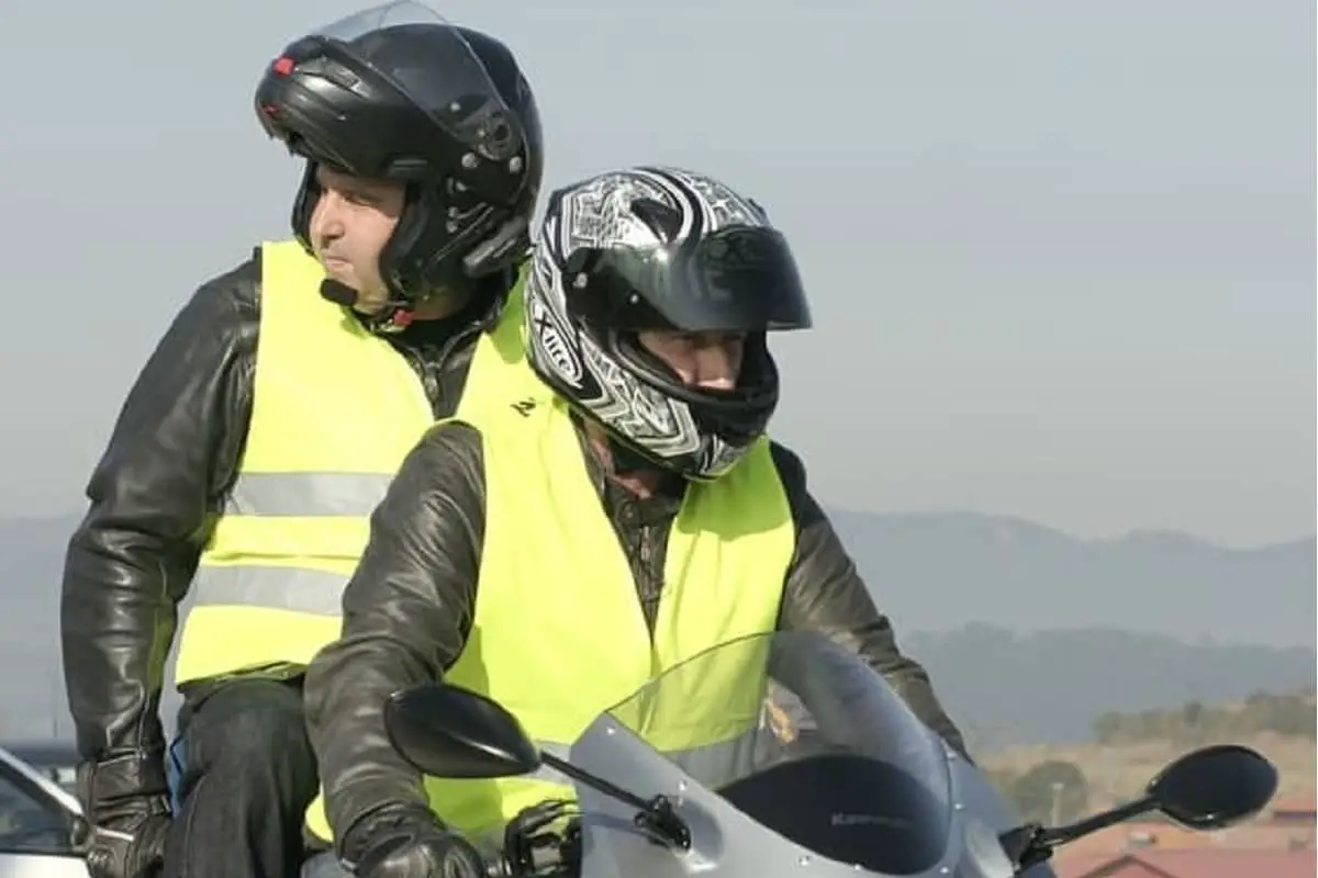 Two men on motorcycle, rider wearing full face helmet and passenger wearing modular helmet