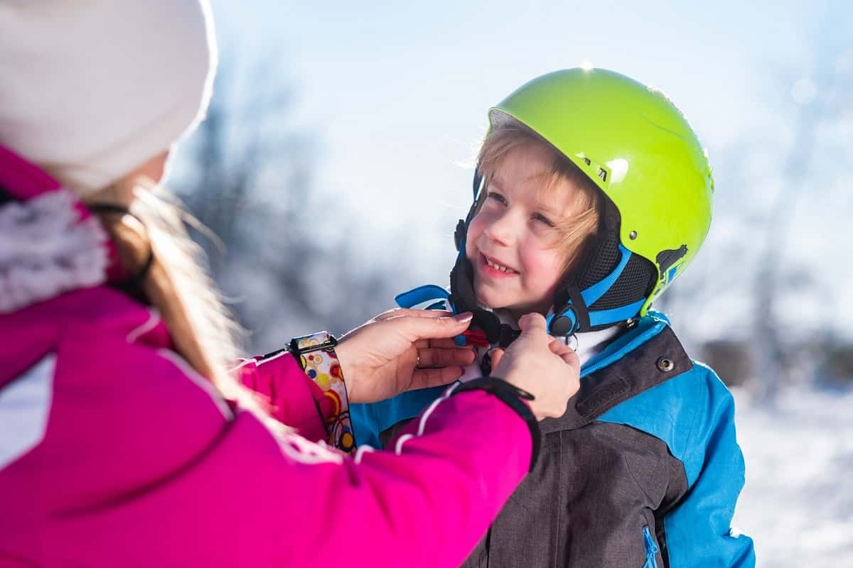 mother adjusting child's ski helmet strap