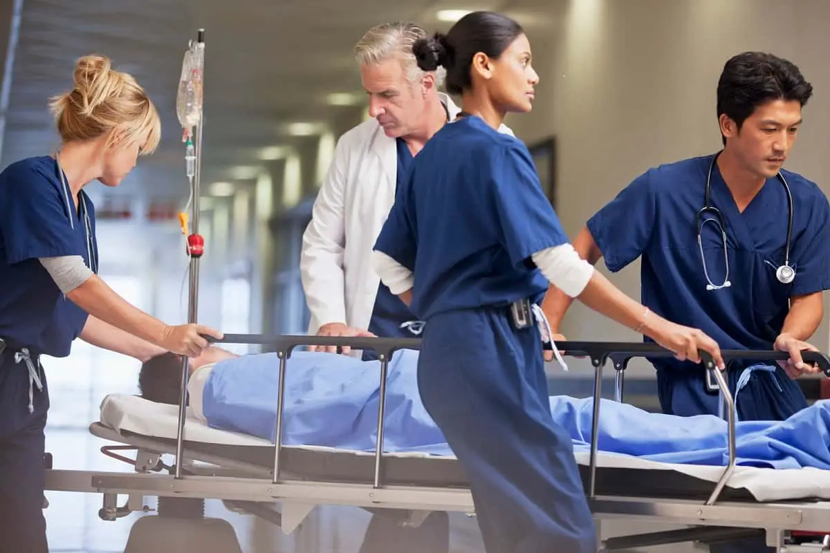 Doctor and nurses wheeling patient on bed through hospital