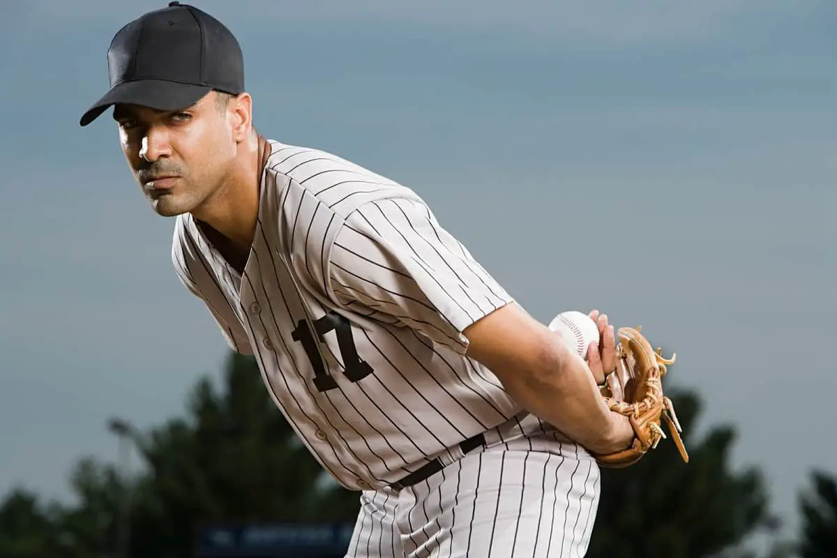 Baseball pitcher with ball behind his back eyeing the batter while he prepares to pitch the ball