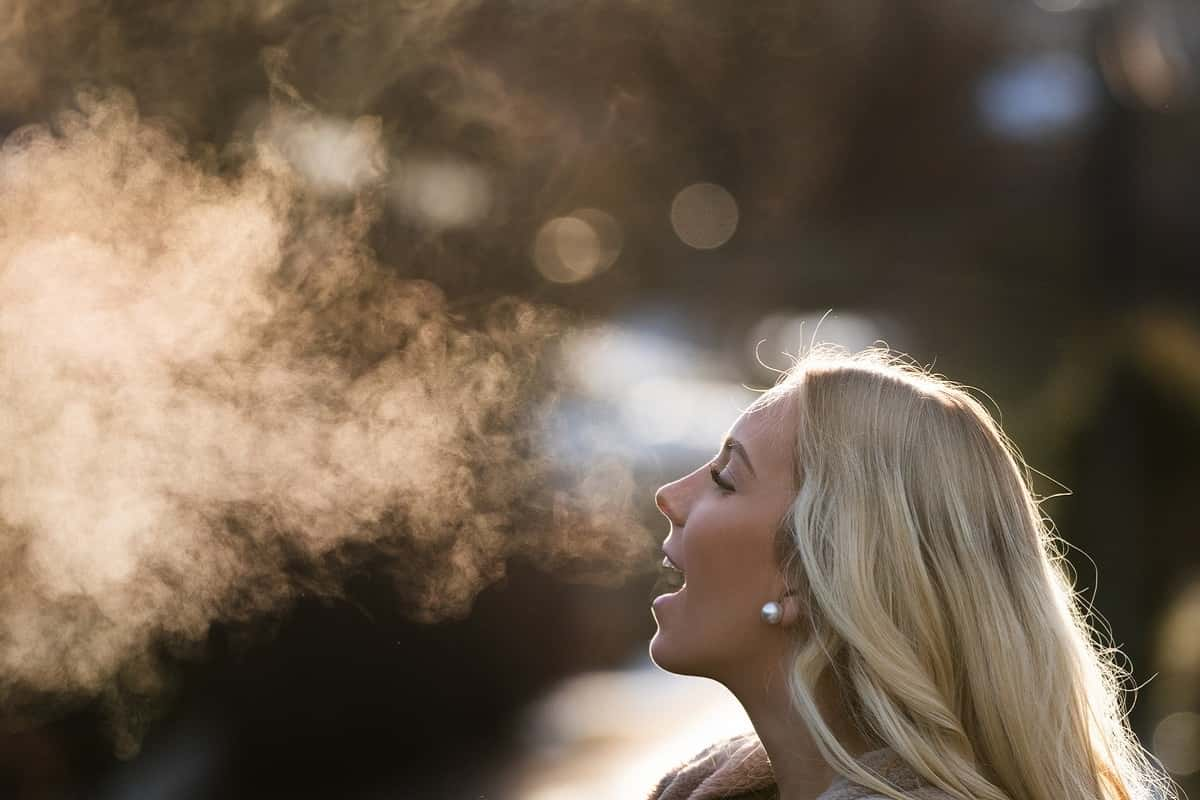 woman breathes out warm air on cold winter day