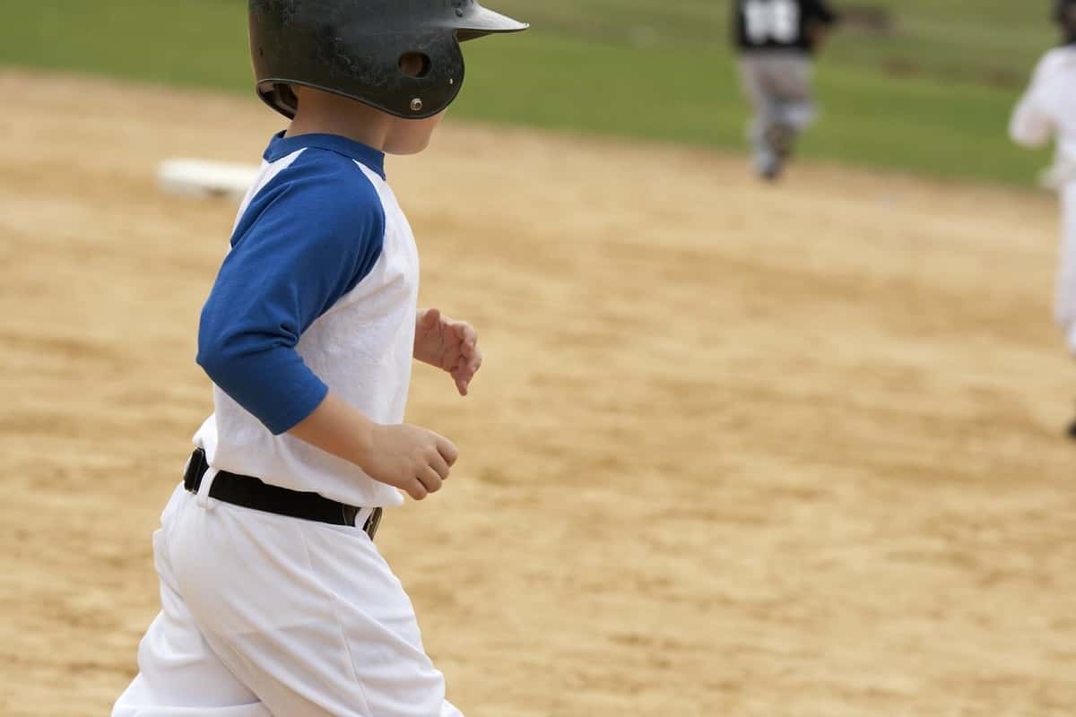 Baseball little leaguer wearing black helmet running between bases