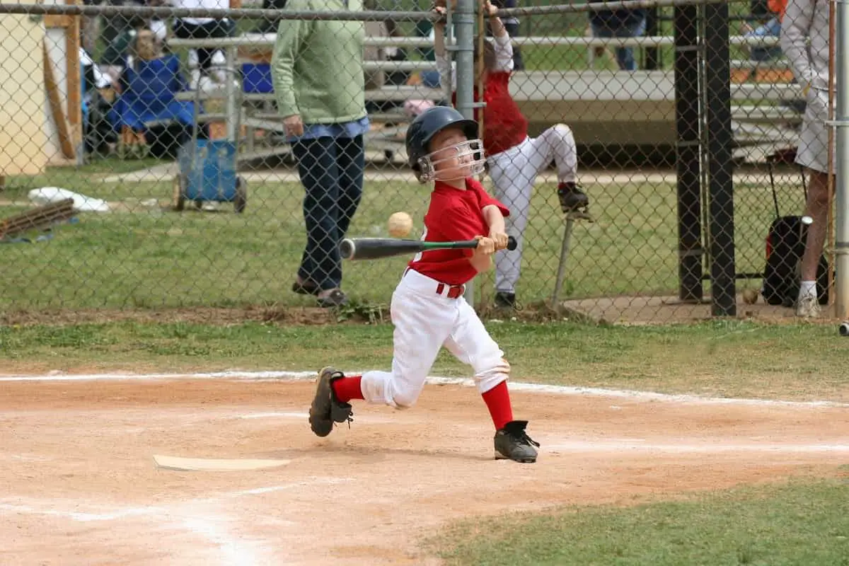 Baseball little league young boy wearing helmet trying to hit the ball