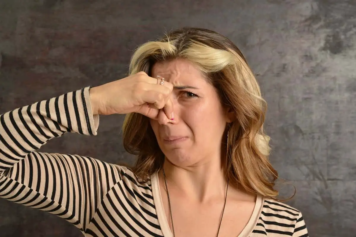 woman holding her nose to avoid a bad smell