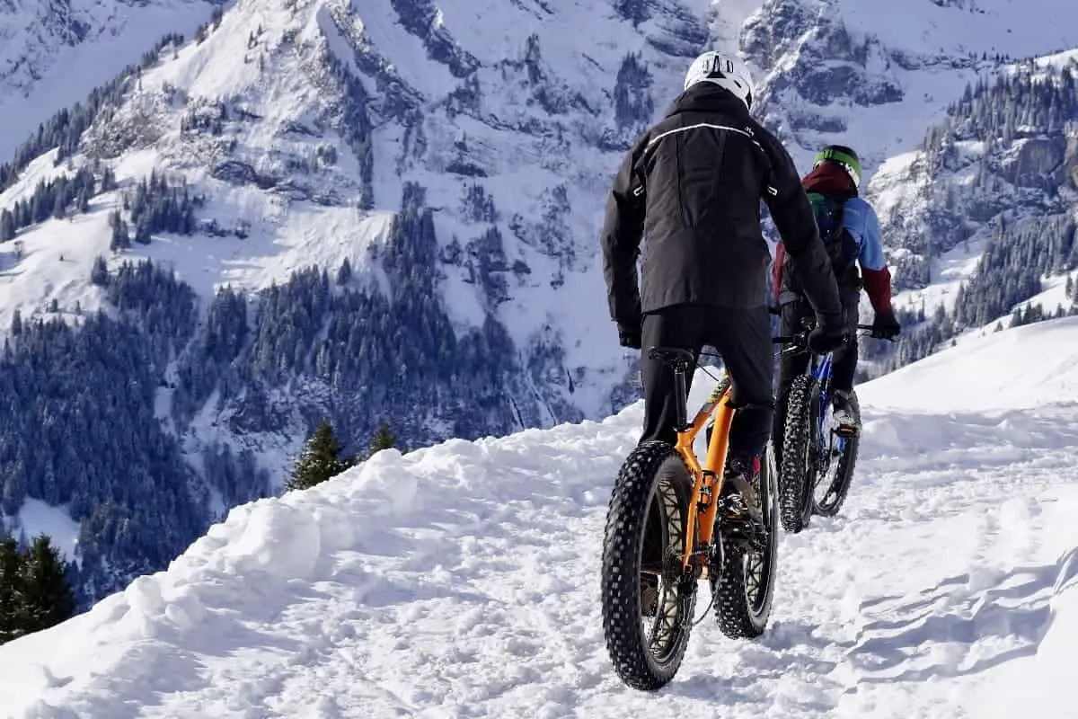 Can you wear a bike helmet skiing? These two cyclists cycling in the snow look like they might try.