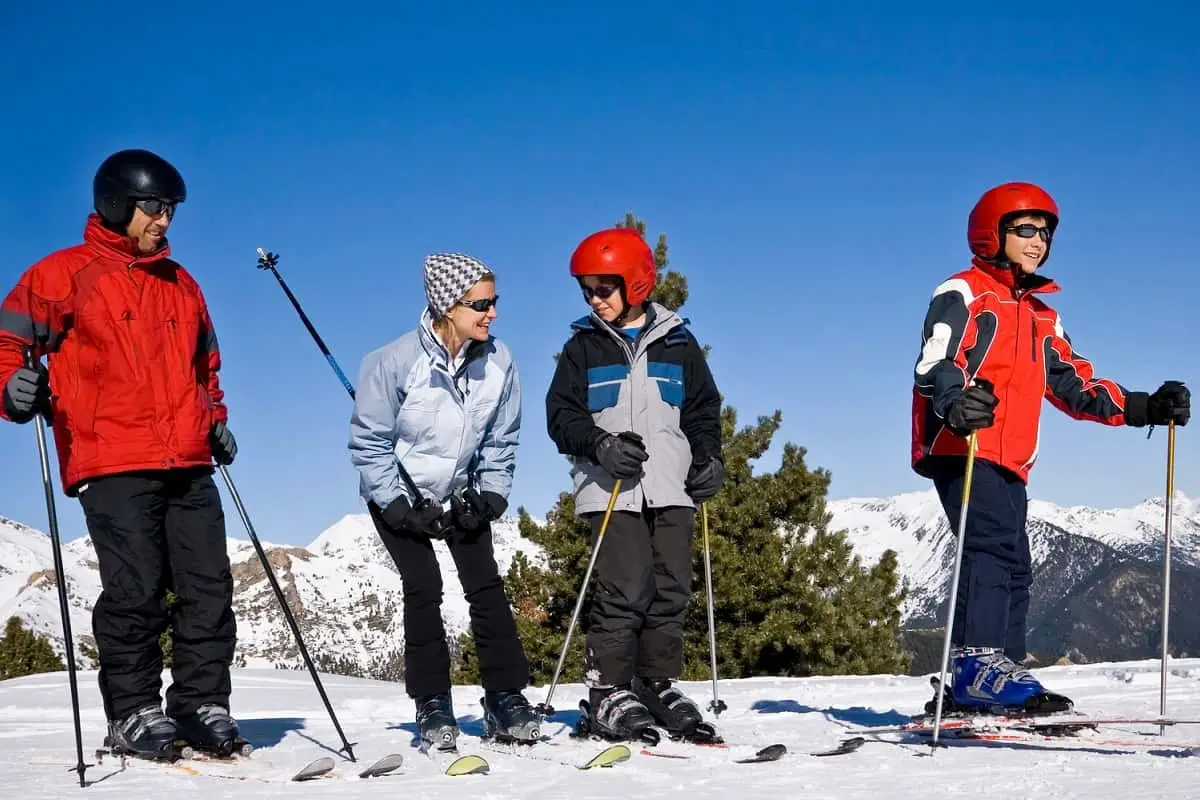 A family group at the snow ready to ski. Do you need a helmet to ski? Looks like mom decided to go without a helmet today!