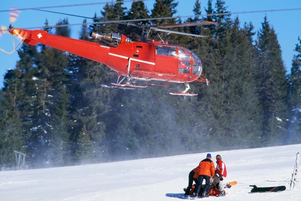 red helicopter prepares to medivac injured snow skier