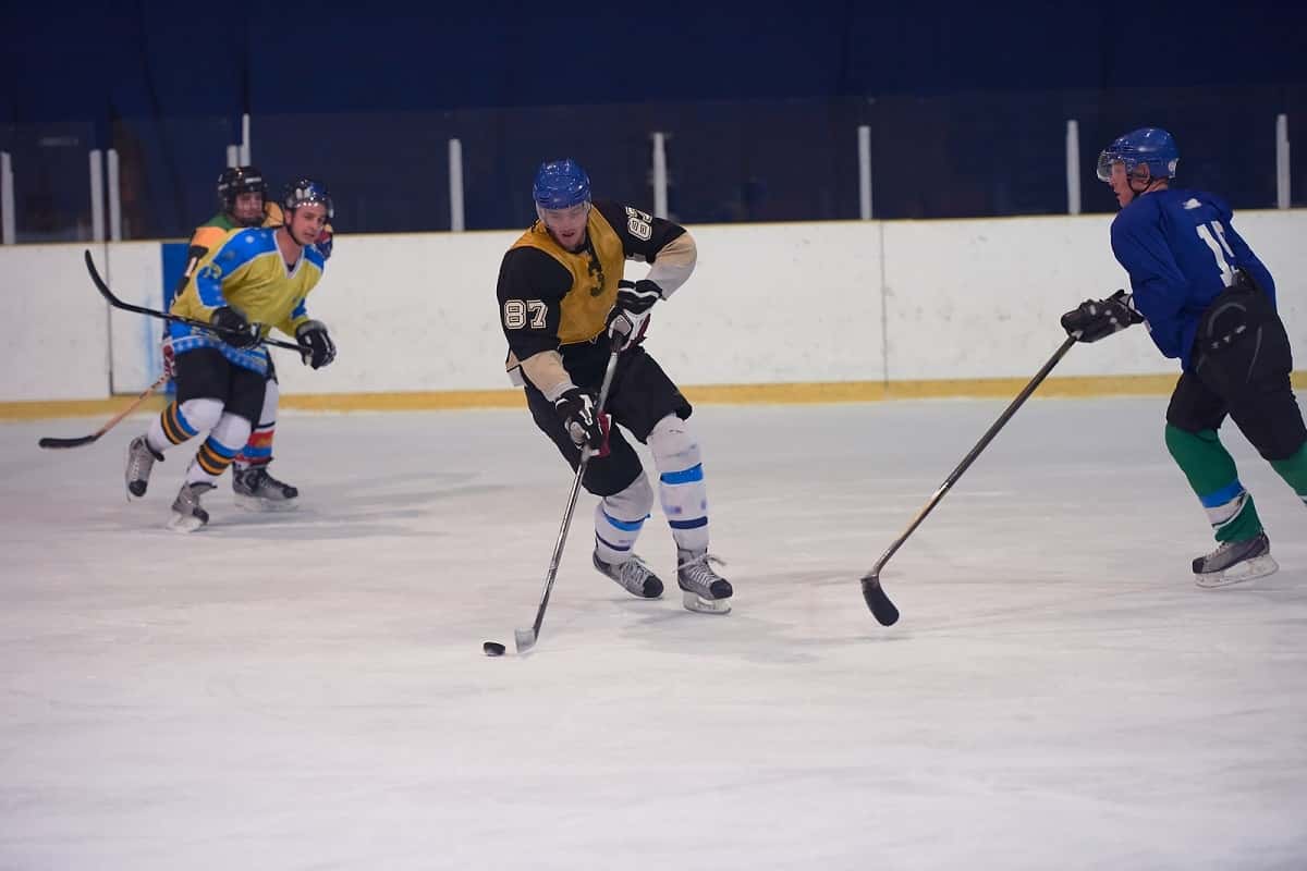 ice hockey game in progress, one player with puck surrounded by 3 other players