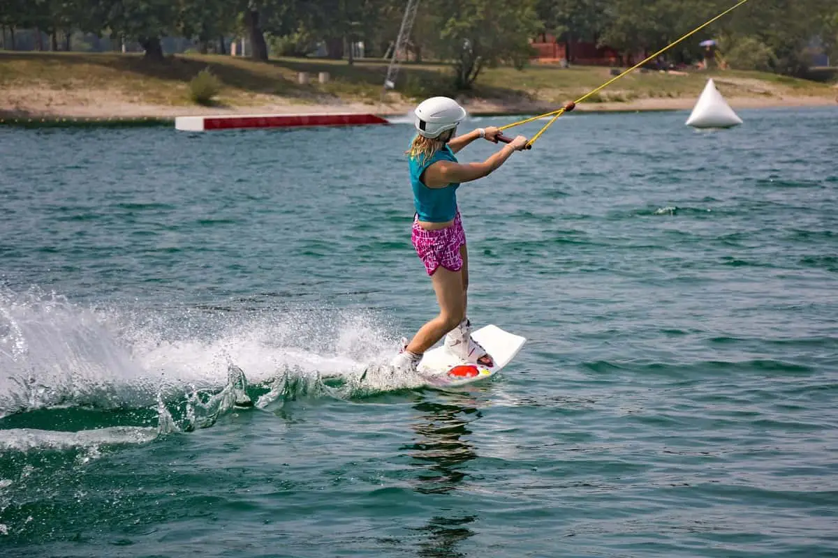 woman wakeboarding on a river wearing a white helmet