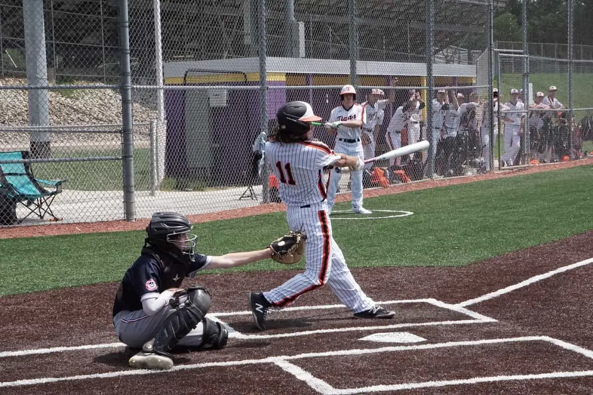 college baseballer wearing striped uniform hitting ball