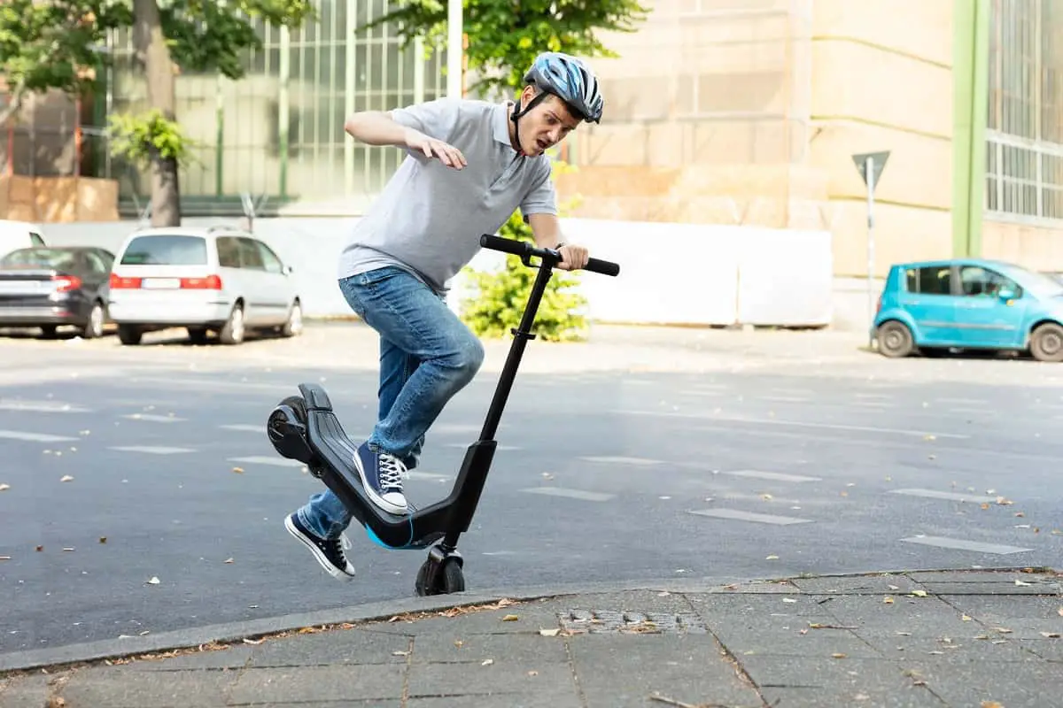 man crashing his electric scooter into the curb