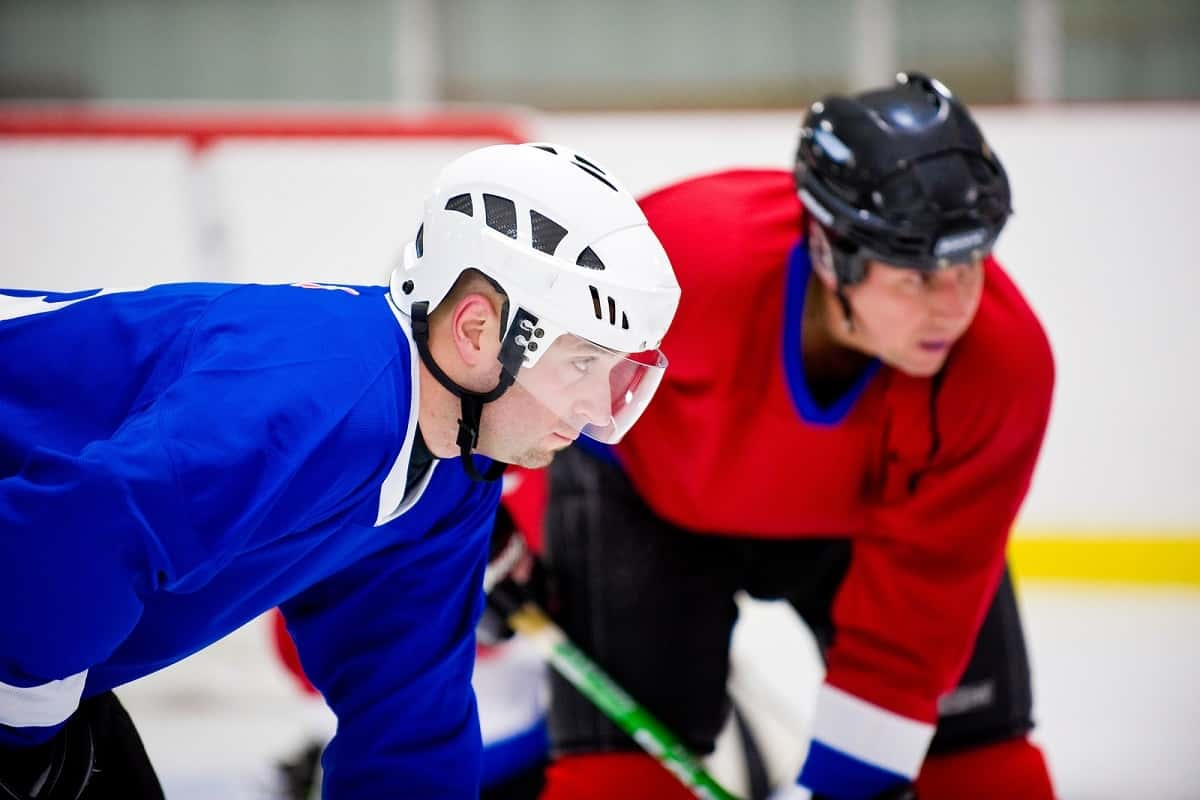 two hockey players wearing different types of helmet concentrating on the game