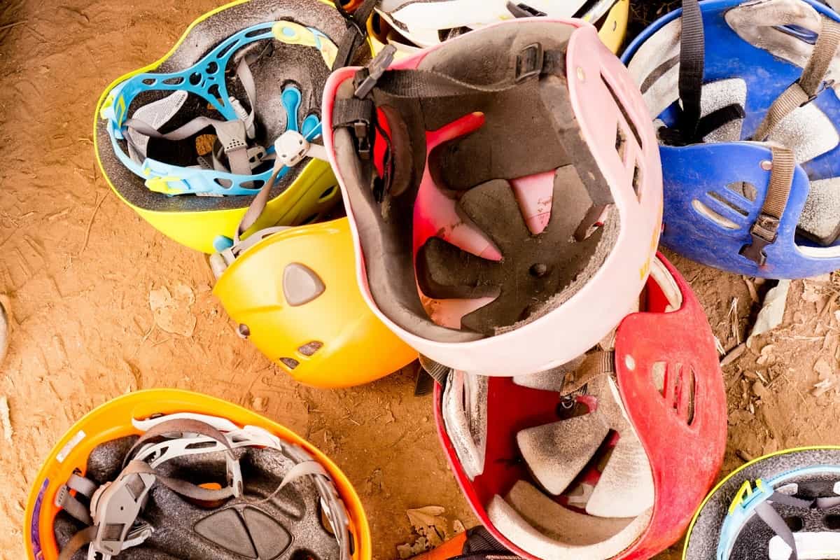 several old helmets of various colors in a pile on the ground