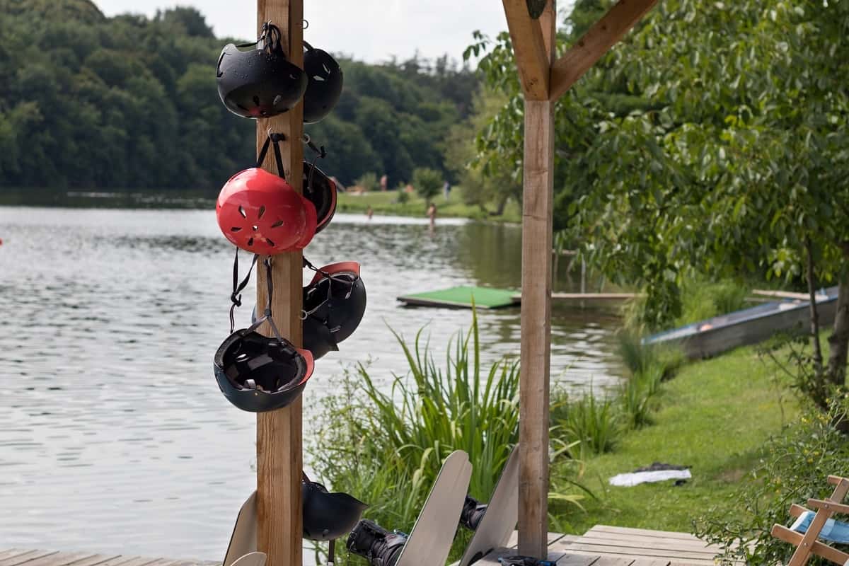 water sport helmets hanging on a post by a jetty on a lake