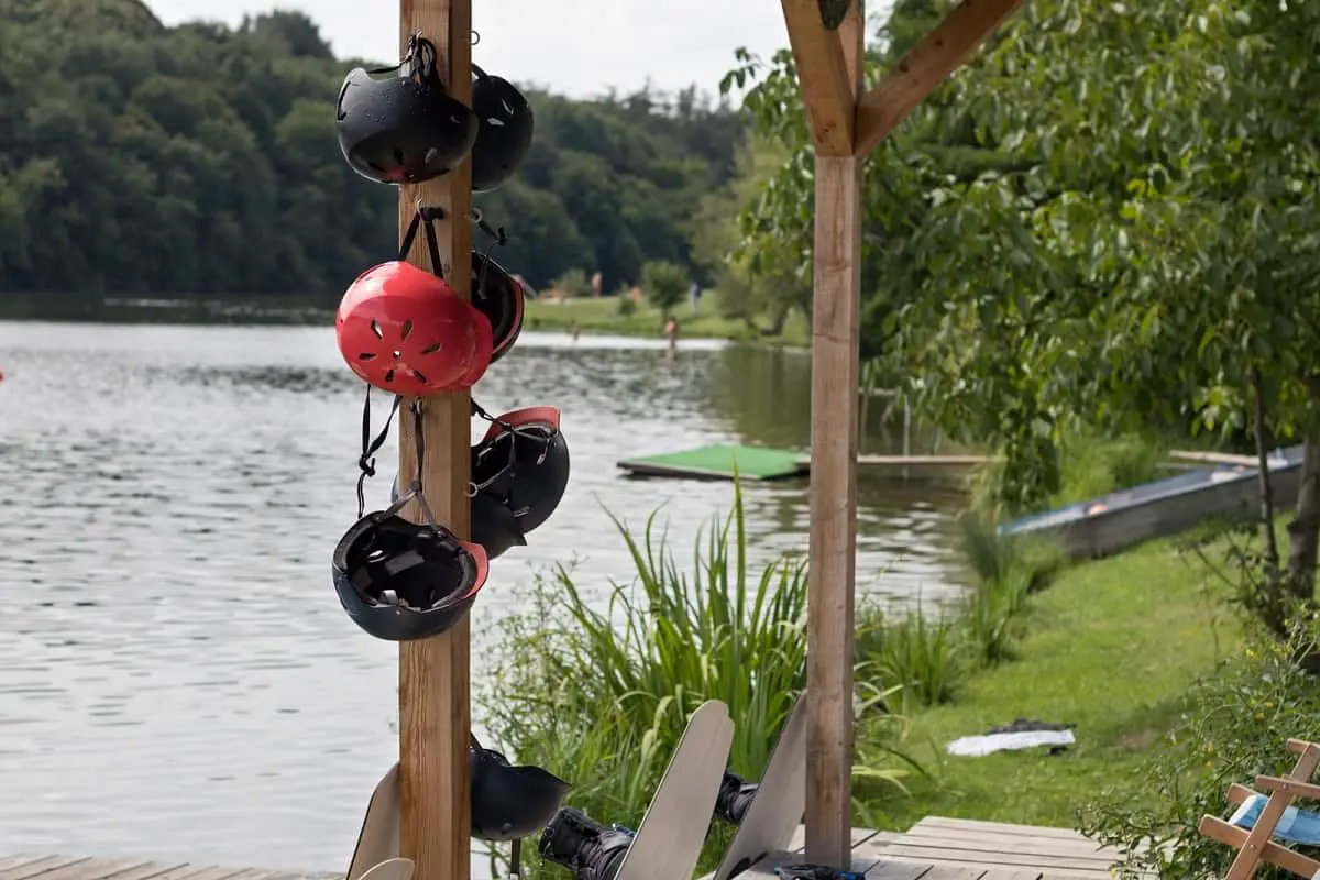 Can I Use a Snowboard Helmet for Wakeboarding? 1 water sport helmets hanging on a post by a jetty on a lake