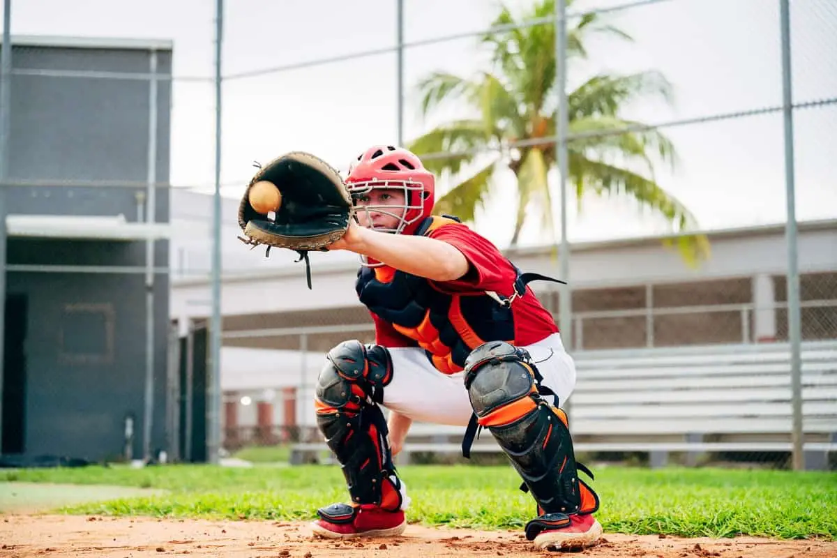 Baseball catcher wearing helmet with cage takes ball in his mitt