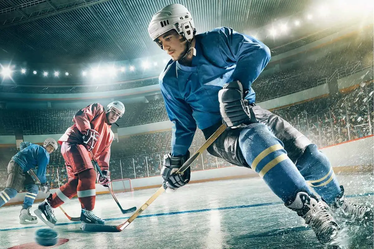 game of ice hockey in progress blue player has possession of puck while red player looks on