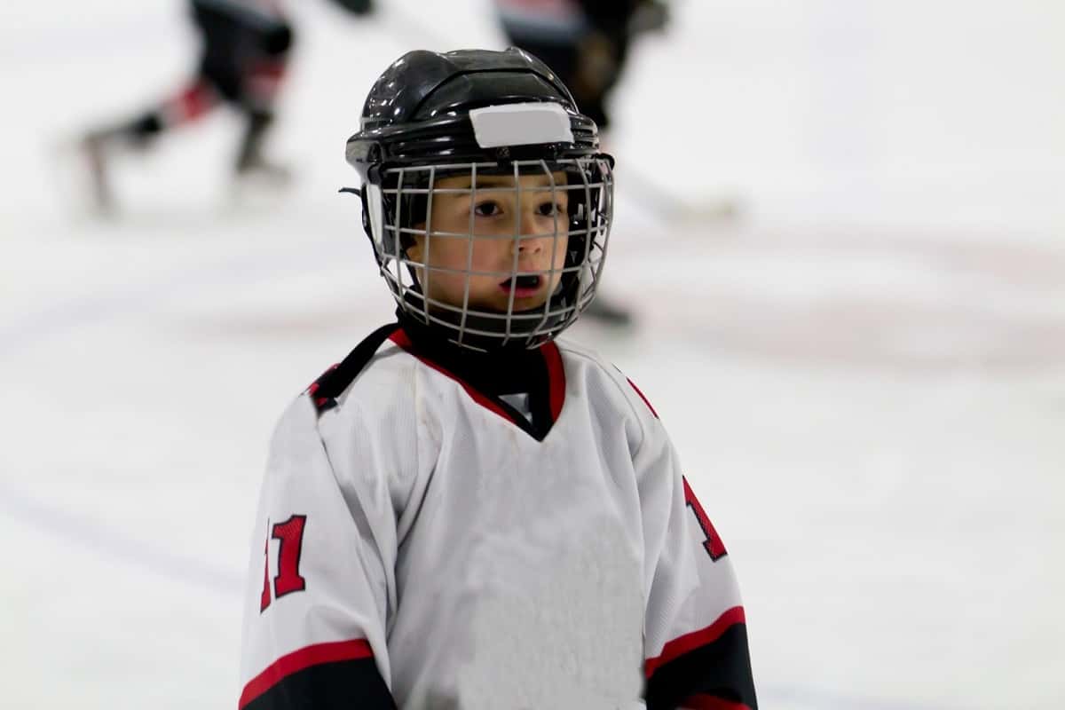 young boy wearing ice hockey helmet standing with his mouth open