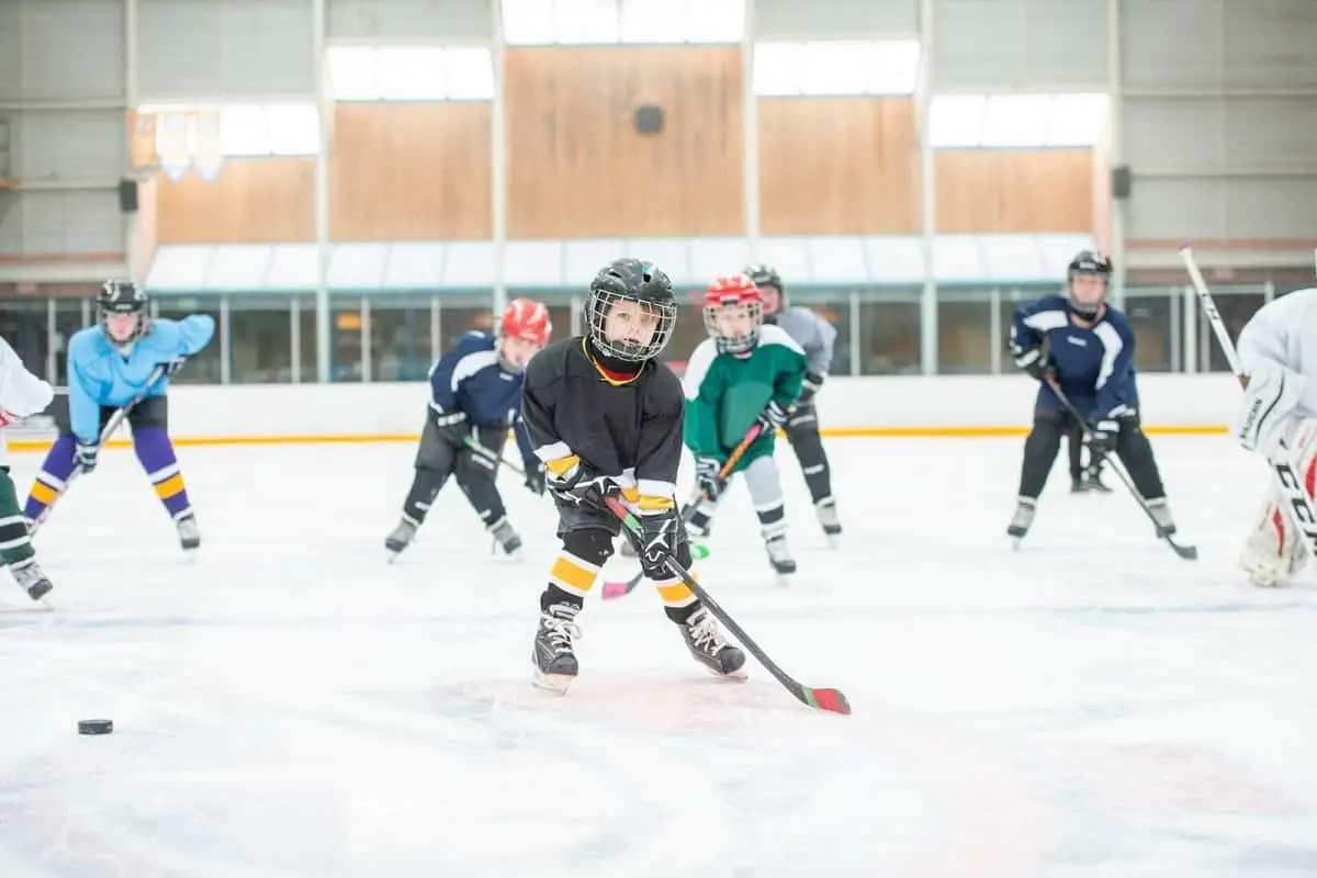 young boys wearing hockey helmets playing ice hocky indoors