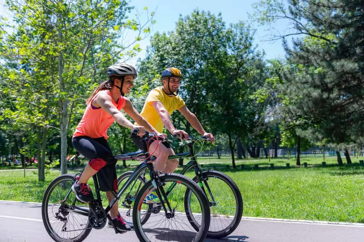 Are expensive bike helmets worth it? Here we have a man and woman bike riding on a road by a parkland wearing expensive cycling helmets.