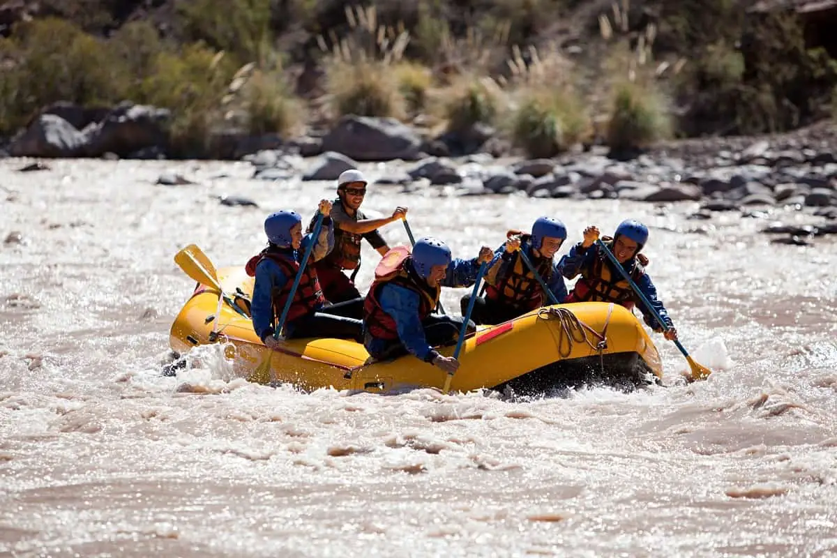 Five people in a yellow rubber raft wearing EN1385 certified watersports helmets