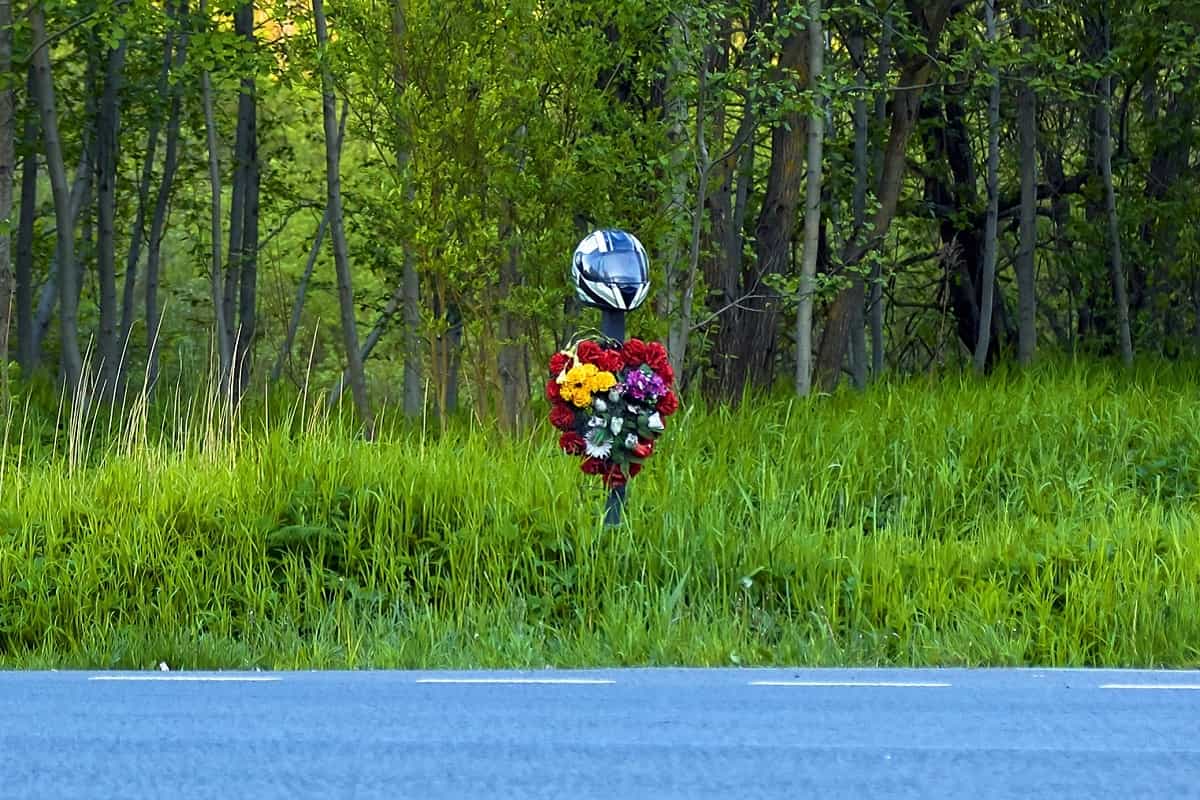 floral wreath at roadside with motorcycle helmet on top