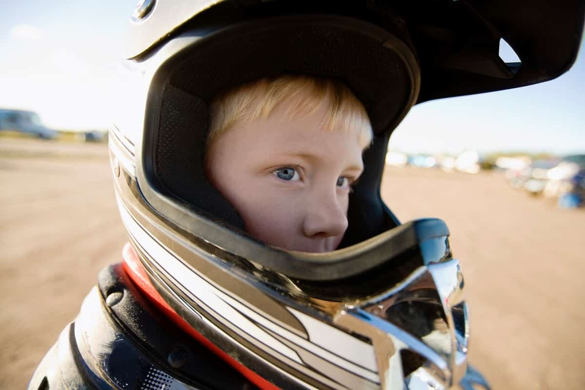 young boy wearing an oversized motocross helmet