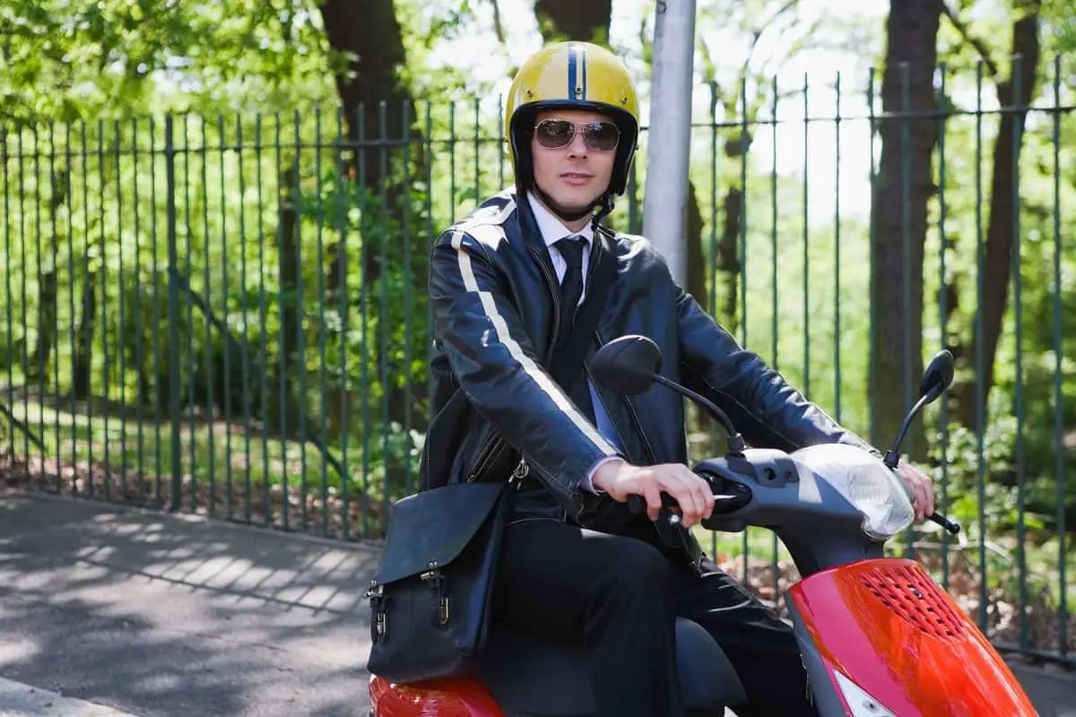 Do you need a helmet for a moped? This man is wearing a yellow helmet while riding his red moped.