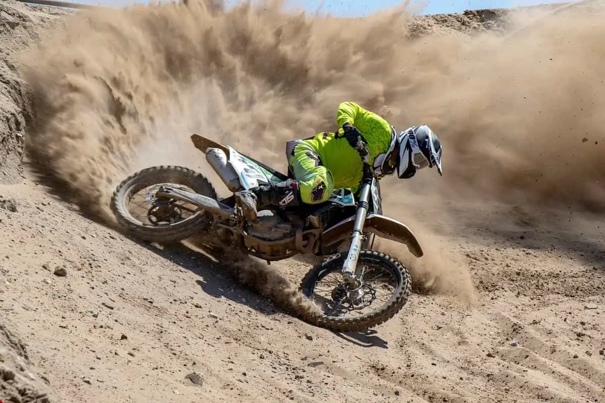 man on a dirt bike kicking up a lot of dirt and dust behind him