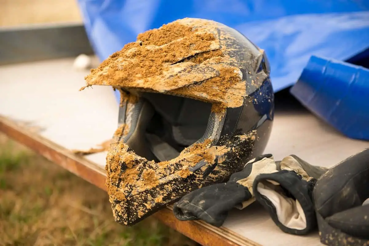 black dirt bike helmet covered with dirt and mud