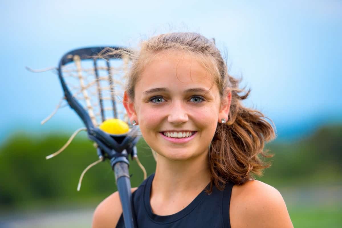 female lacrosse player holding lacrosse stick with yellow ball