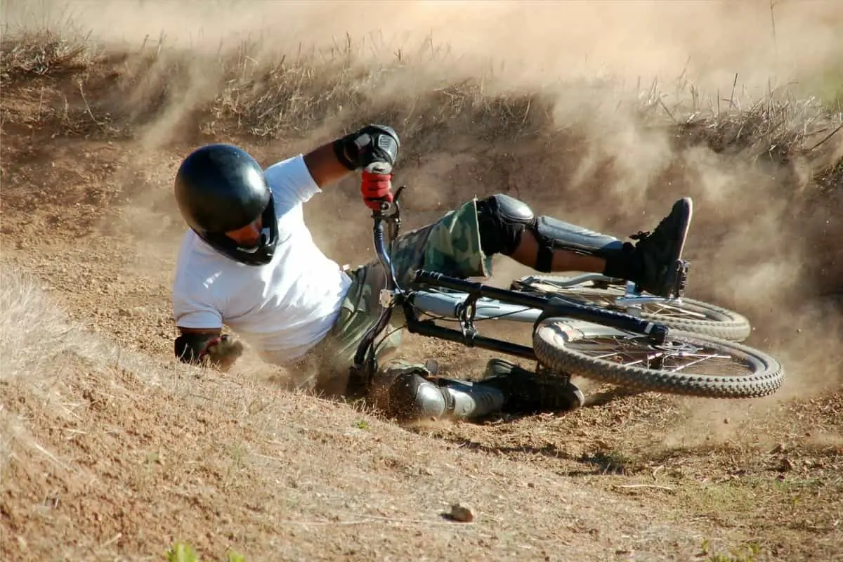 mountain bike rider wearing full face helmet takes a fall while cornering on dirt track