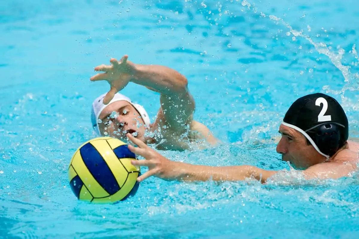 two opposing water polo players going for the ball