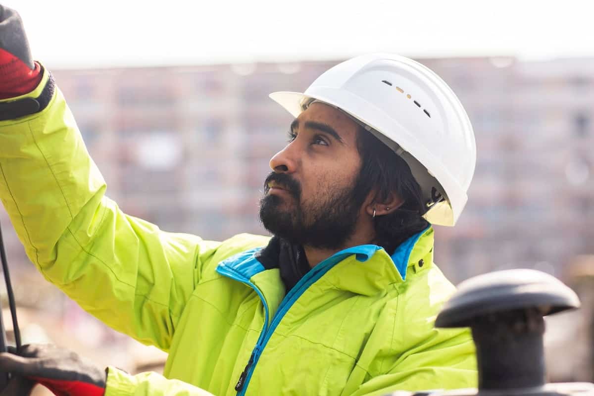 bearded construction worker wearing white hard hat and yellow long sleeved jacket